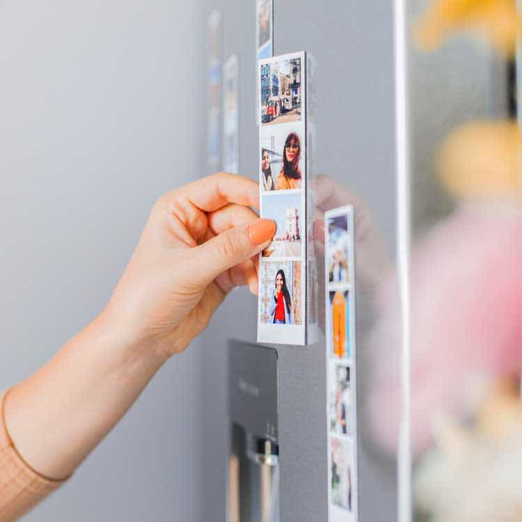 A woman sticking our photobooth print-out on her fridge. Our photo booth hire prices increase slightly for this feature